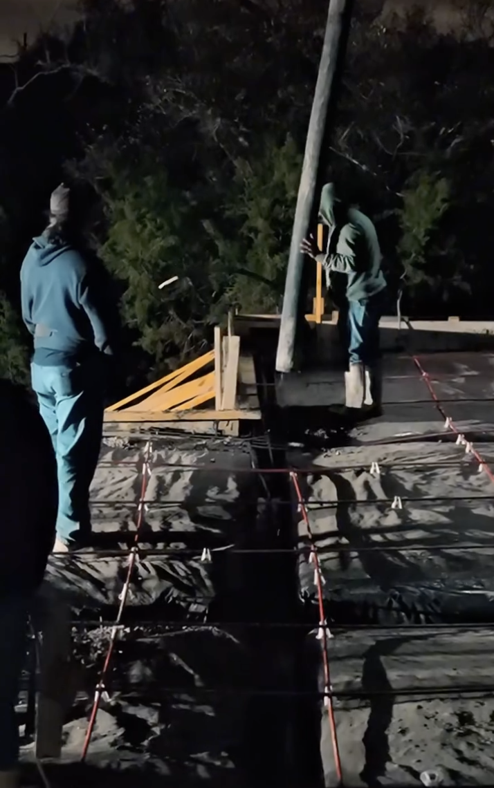 Crew guiding concrete into reinforced forms at night