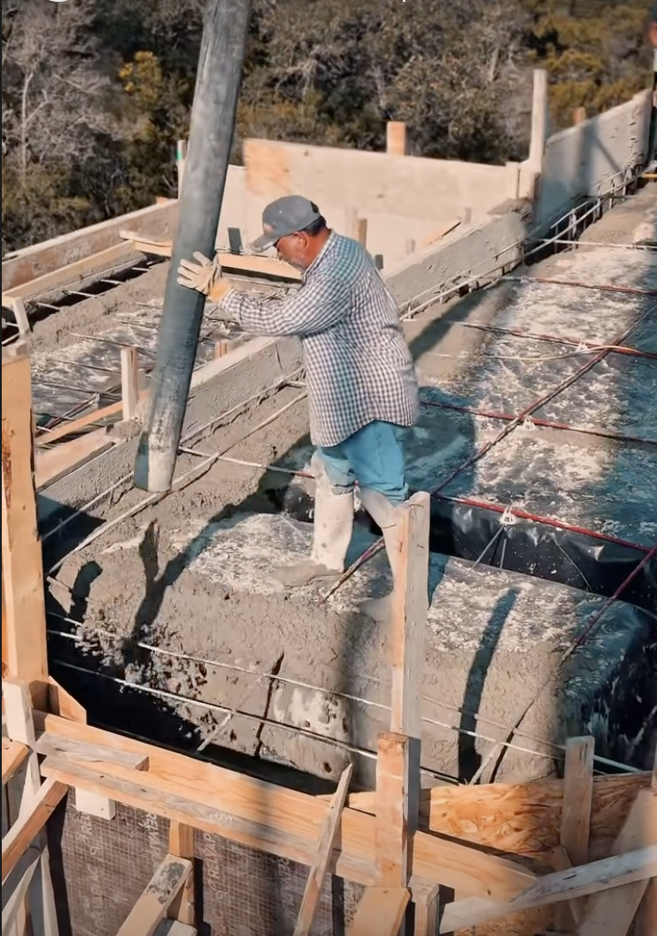 Crew member directing concrete into reinforced forms