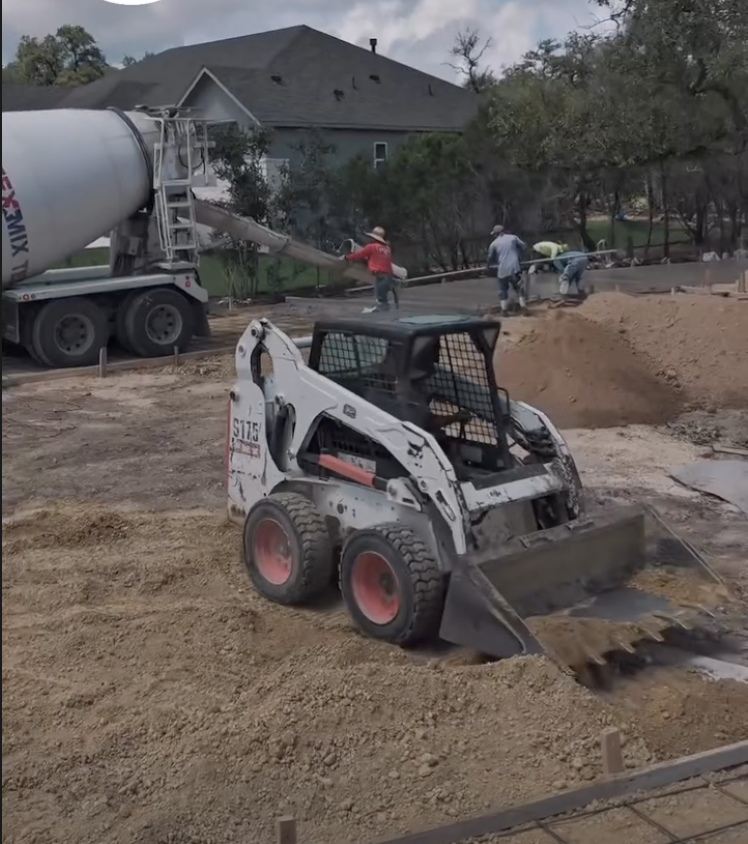 Skid steer supporting an active concrete pour