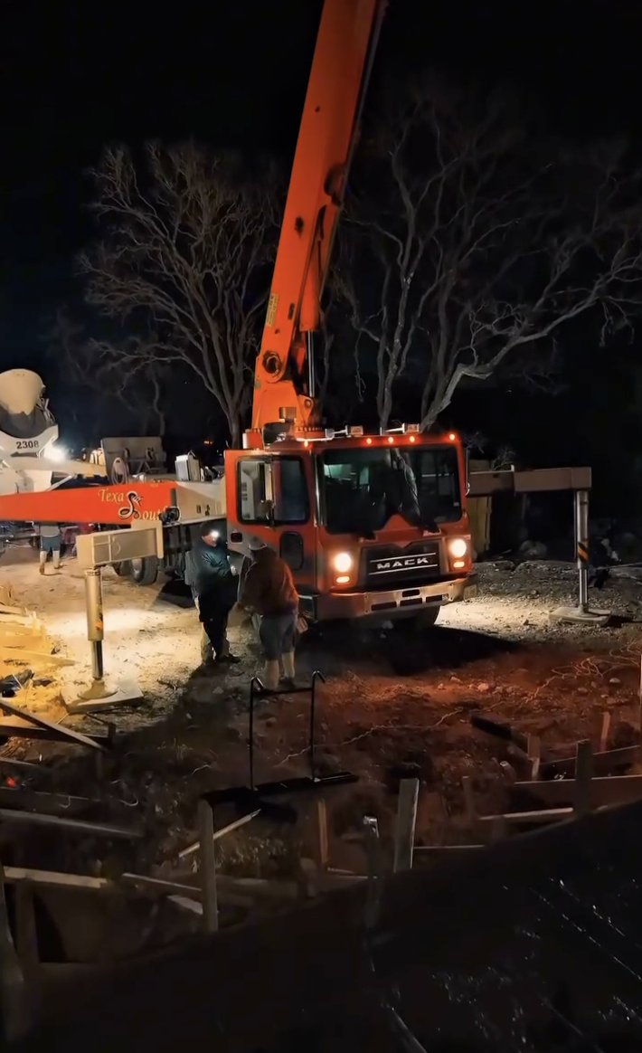 Orange concrete pump operating at night