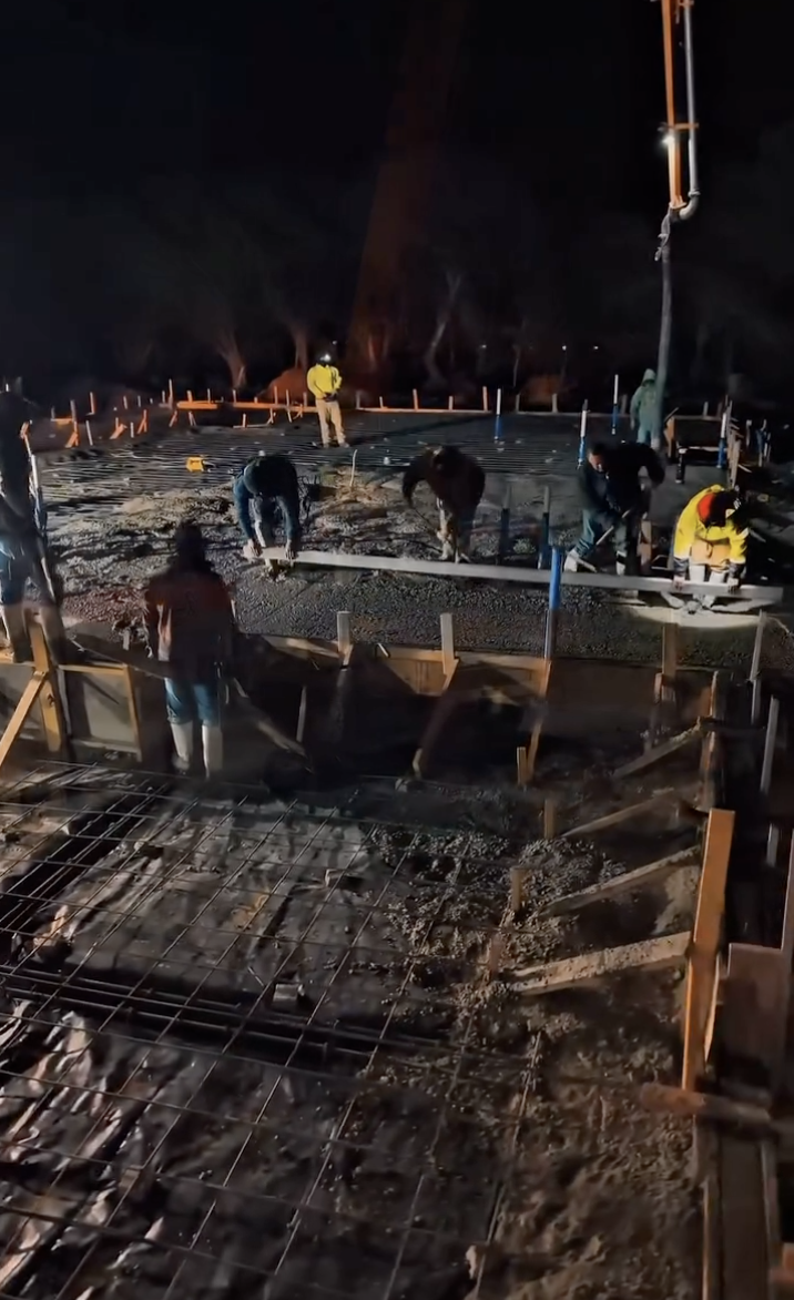 Crew finishing a slab under work lights