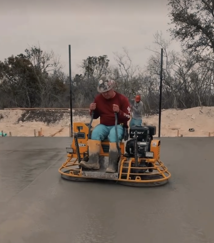 Operator riding a concrete power trowel